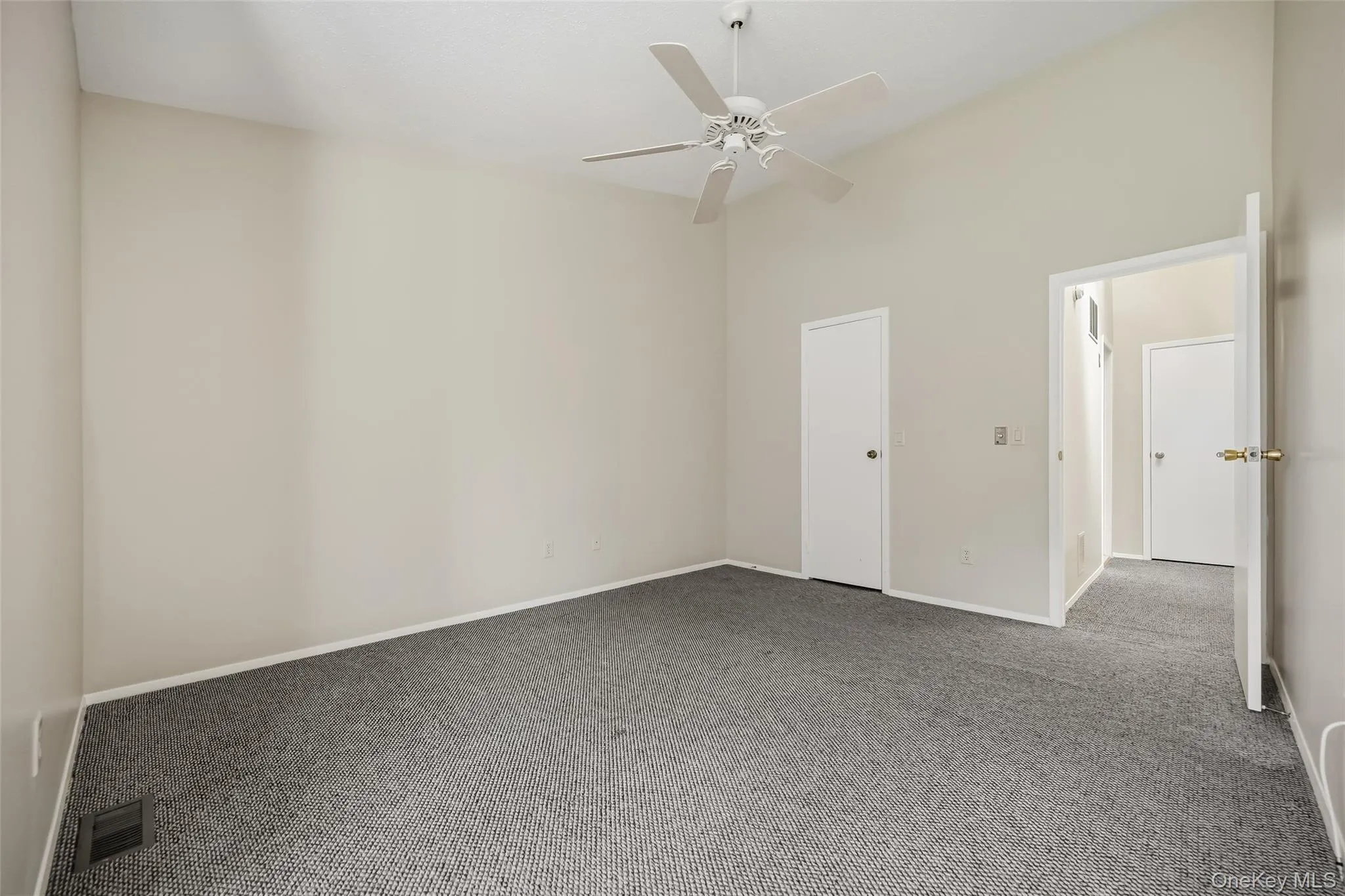 Vaulted ceiling, ceiling fan, neutral wall tones, and carpeting Vaulted ceiling, ceiling fan, neutral wall tones, and carpeting