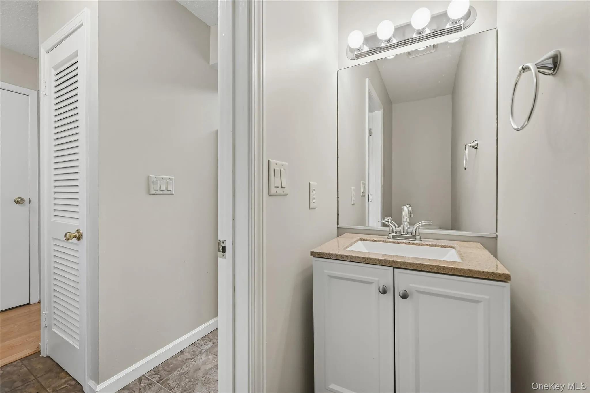 White vanity with cabinet storage, integrated sink, and stone-finish countertop White vanity with cabinet storage, integrated sink, and stone-finish countertop