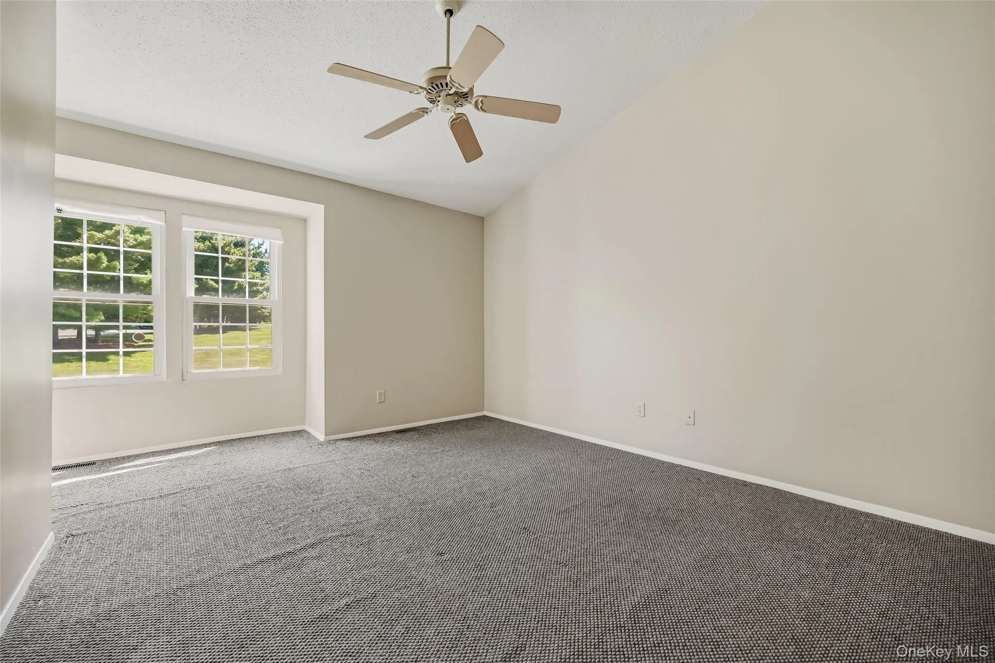 Vaulted ceiling, ceiling fan, neutral wall tones, and carpeting Vaulted ceiling, ceiling fan, neutral wall tones, and carpeting
