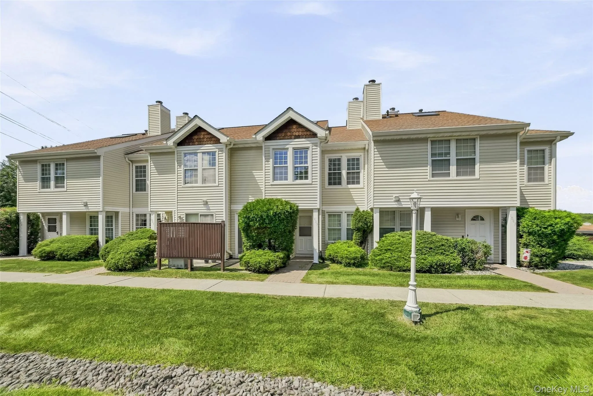 Multi-level townhome featuring light-toned siding, gabled rooflines, and multiple windows Multi-level townhome featuring light-toned siding, gabled rooflines, and multiple windows