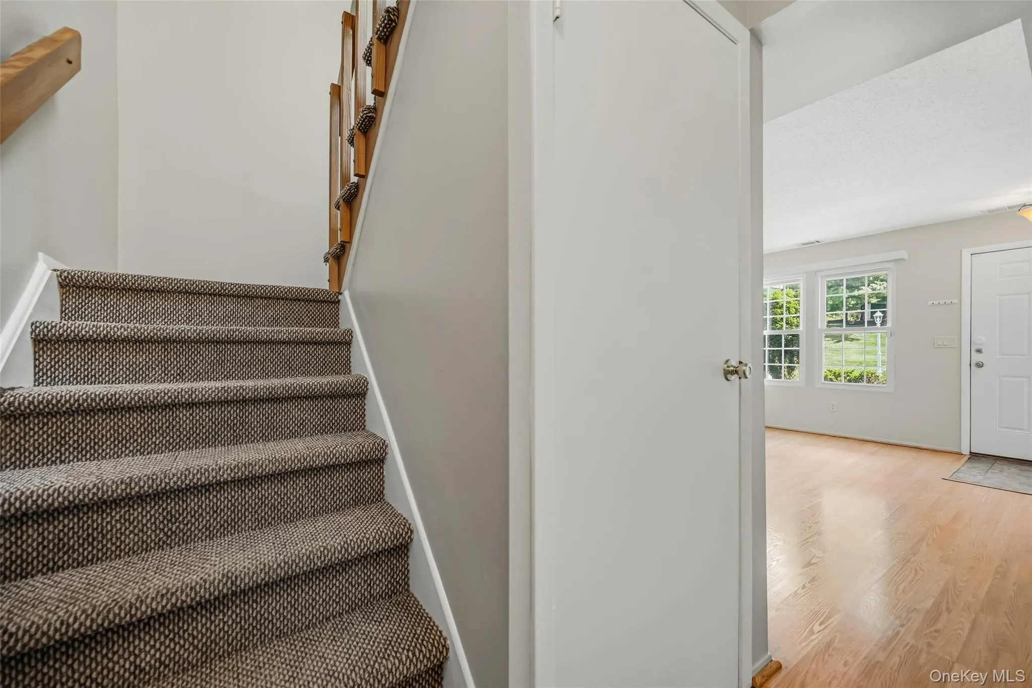 Carpeted staircase with wood handrail, wood-finish flooring Carpeted staircase with wood handrail, wood-finish flooring