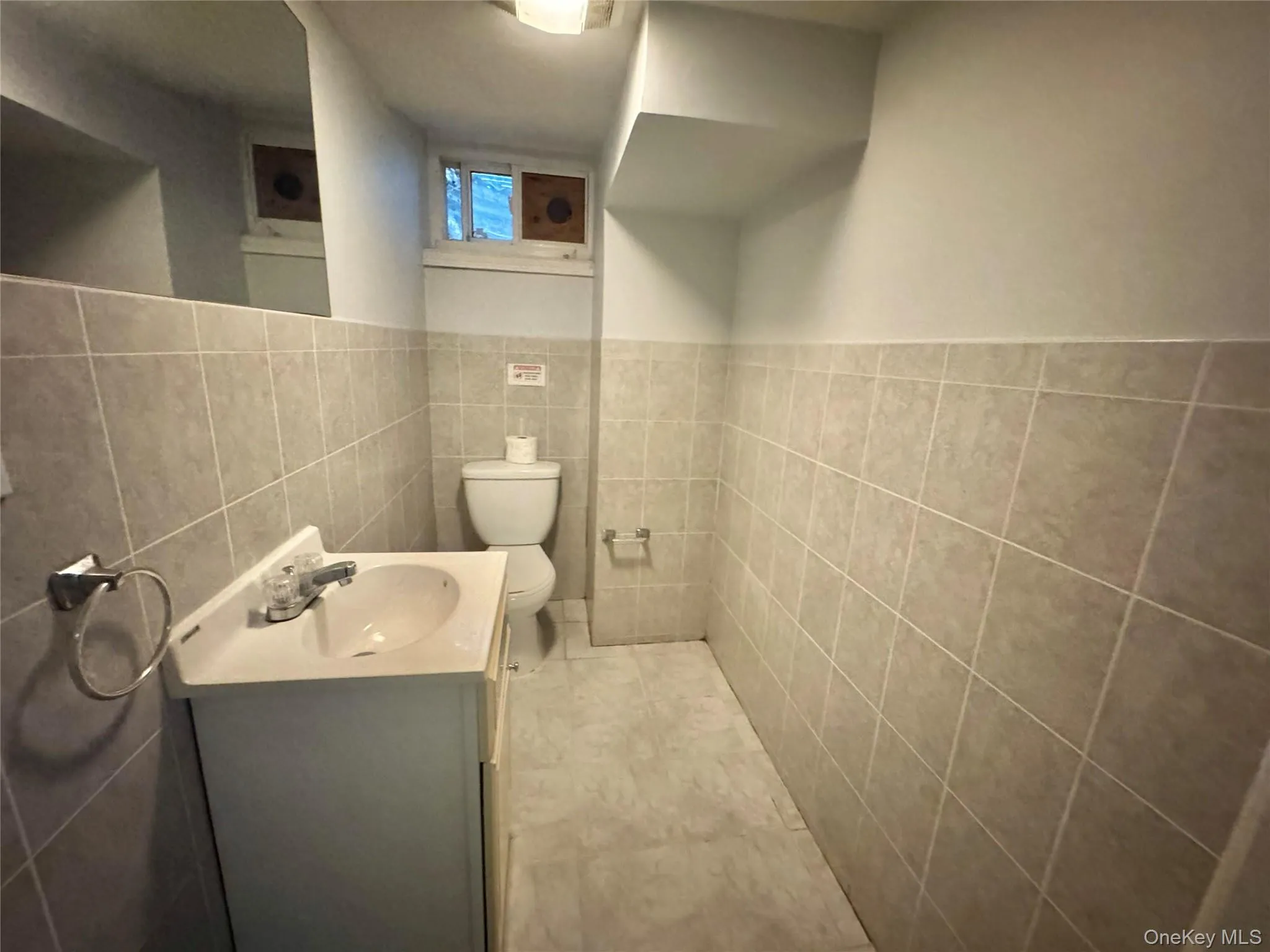 Basement Half Bathroom. Tiled walls and floor, vanity with integrated sink, and a commode Basement Half Bathroom. Tiled walls and floor, vanity with integrated sink, and a commode