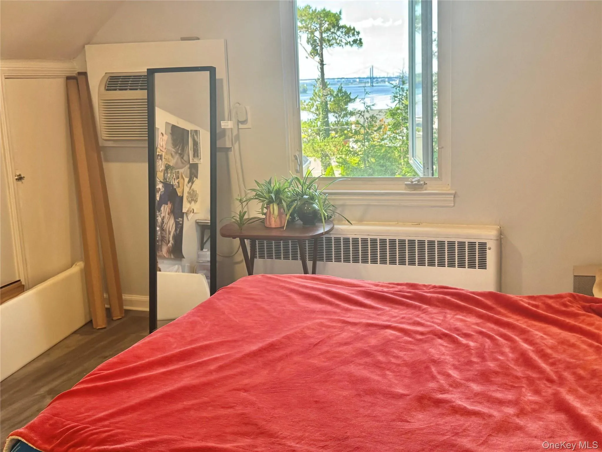 Window offering a scenic water backdrop, window-mounted air conditioning unit, and baseboard heating Window offering a scenic water backdrop, window-mounted air conditioning unit, and baseboard heating