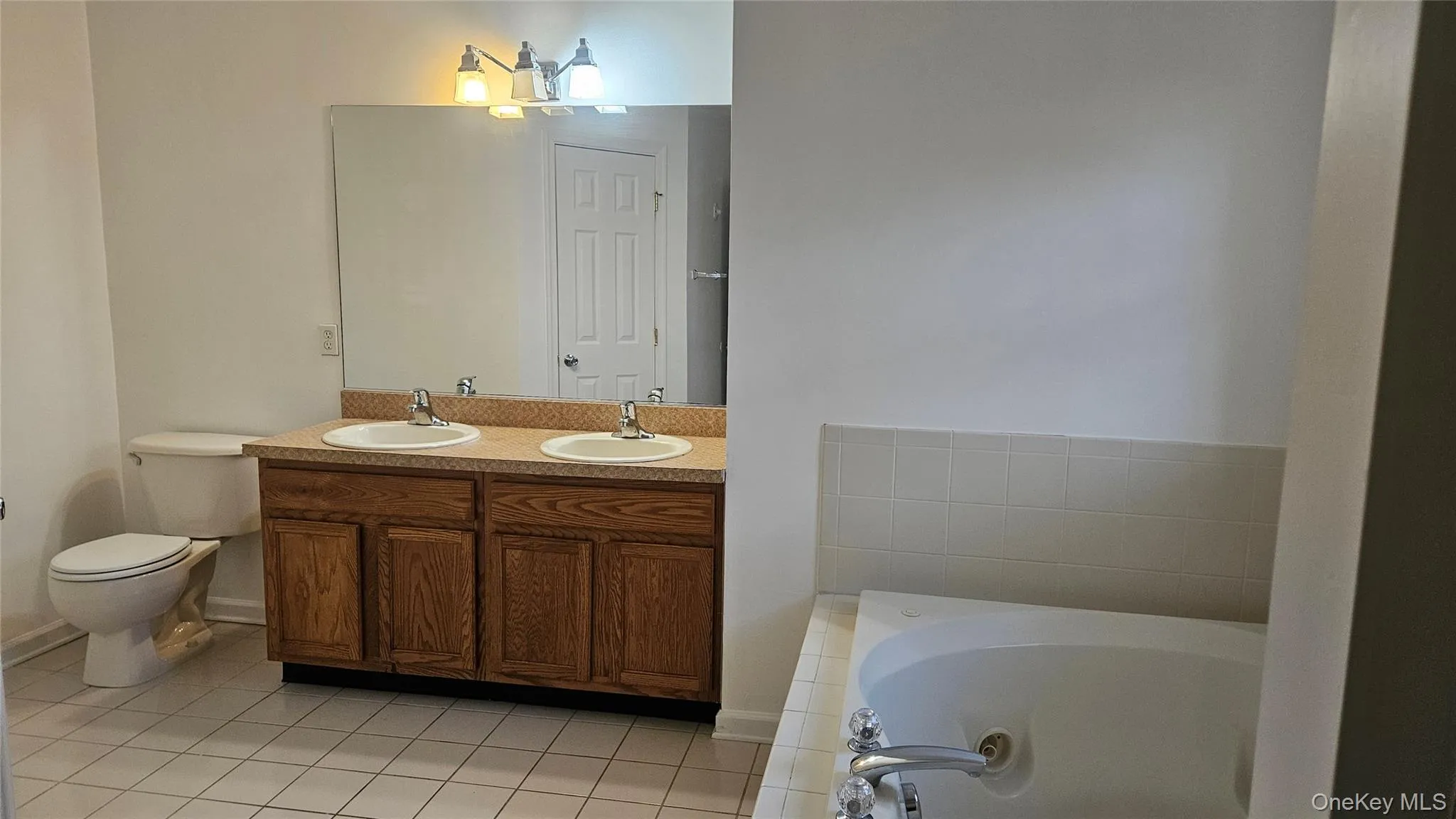 Bathroom featuring a garden tub, tile patterned flooring, toilet, a sink, and double vanity Bathroom featuring a garden tub, tile patterned flooring, toilet, a sink, and double vanity