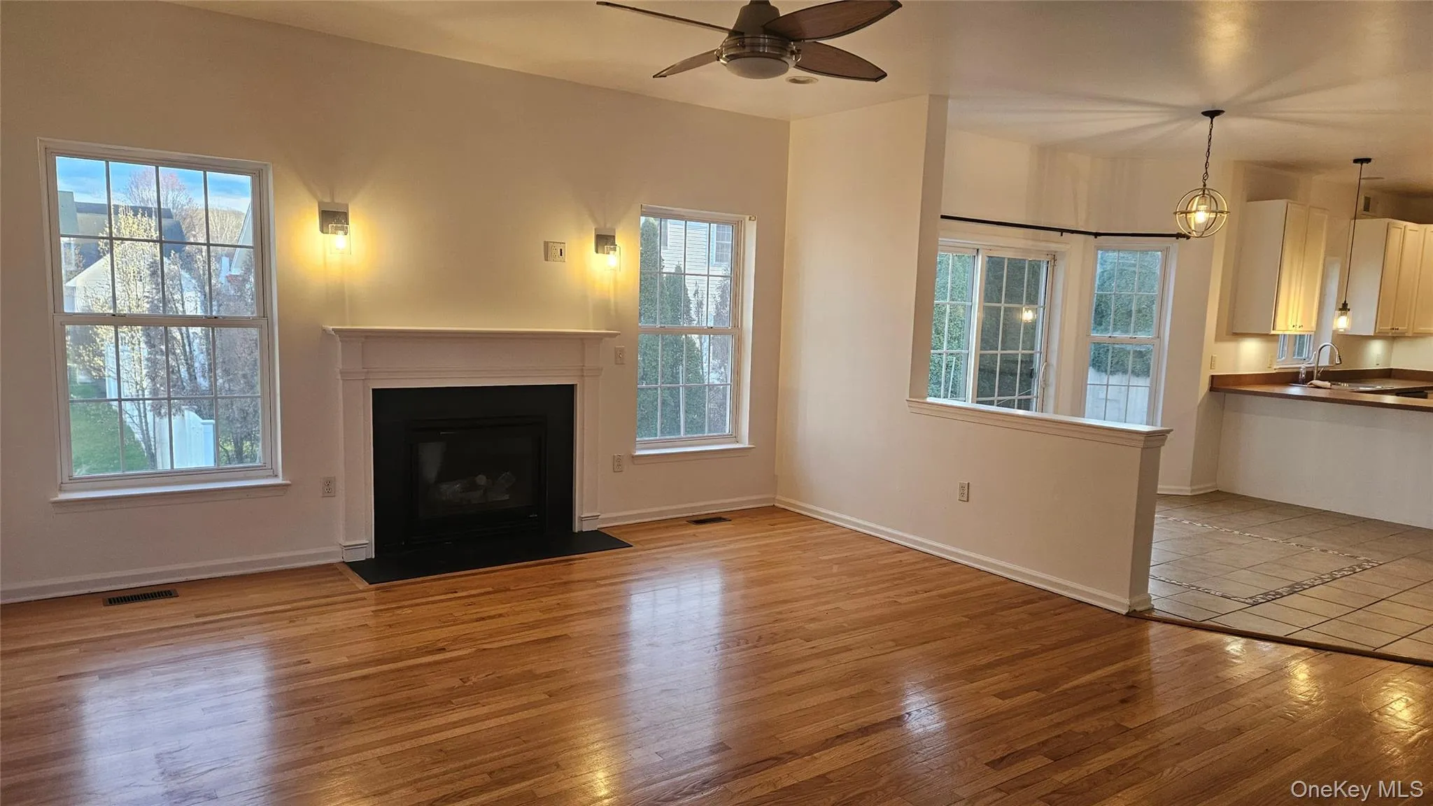 Family room featuring ceiling fan, visible vents, a sink, light wood finished floors, and baseboards Family room featuring ceiling fan, visible vents, a sink, light wood finished floors, and baseboards
