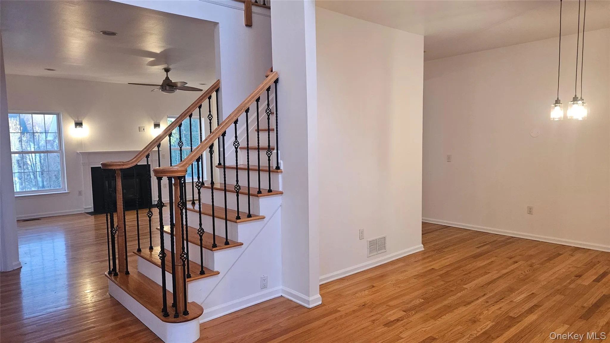 Stairway featuring visible vents, baseboards, a ceiling fan, and wood finished floors Stairway featuring visible vents, baseboards, a ceiling fan, and wood finished floors