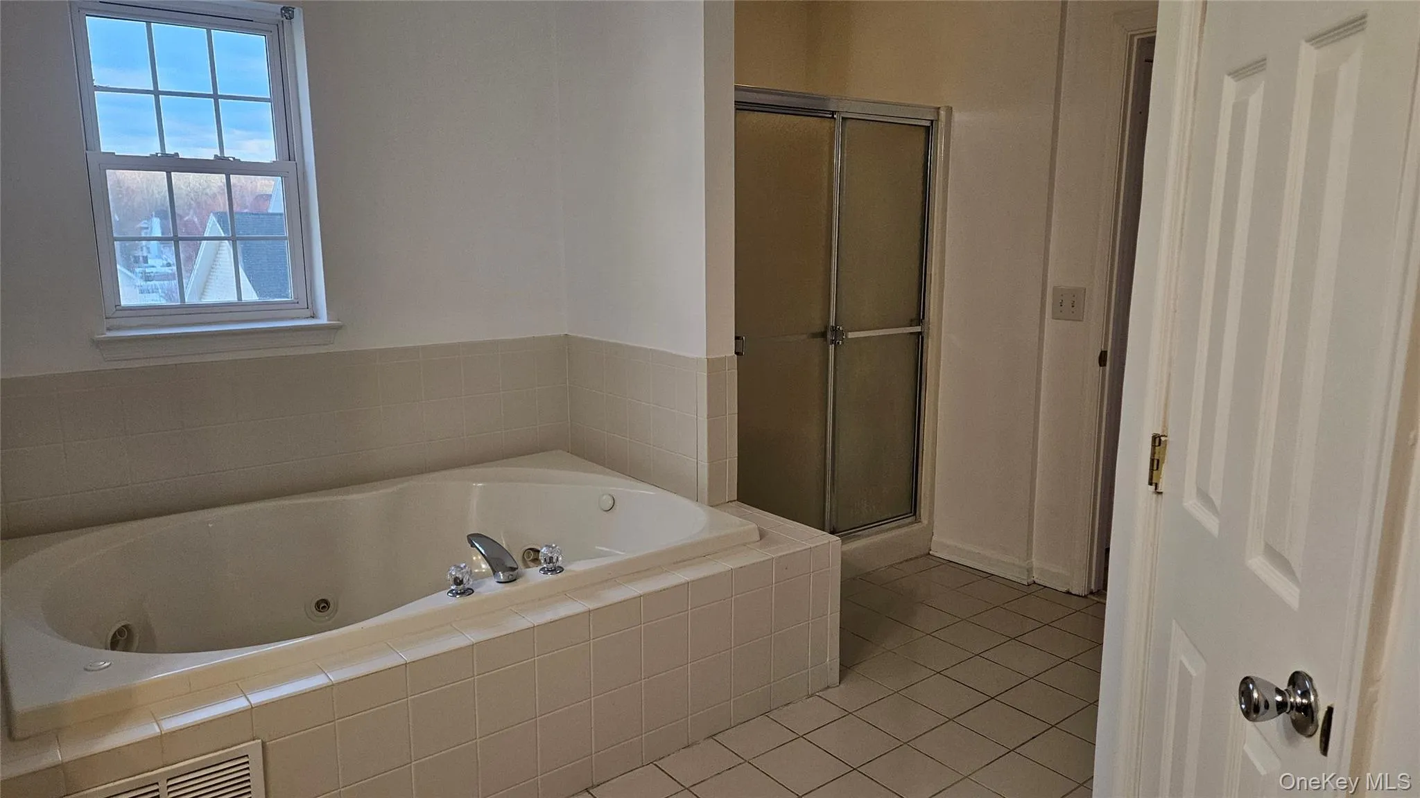 Full bathroom featuring a shower stall, tile patterned flooring, and a tub with jets Full bathroom featuring a shower stall, tile patterned flooring, and a tub with jets