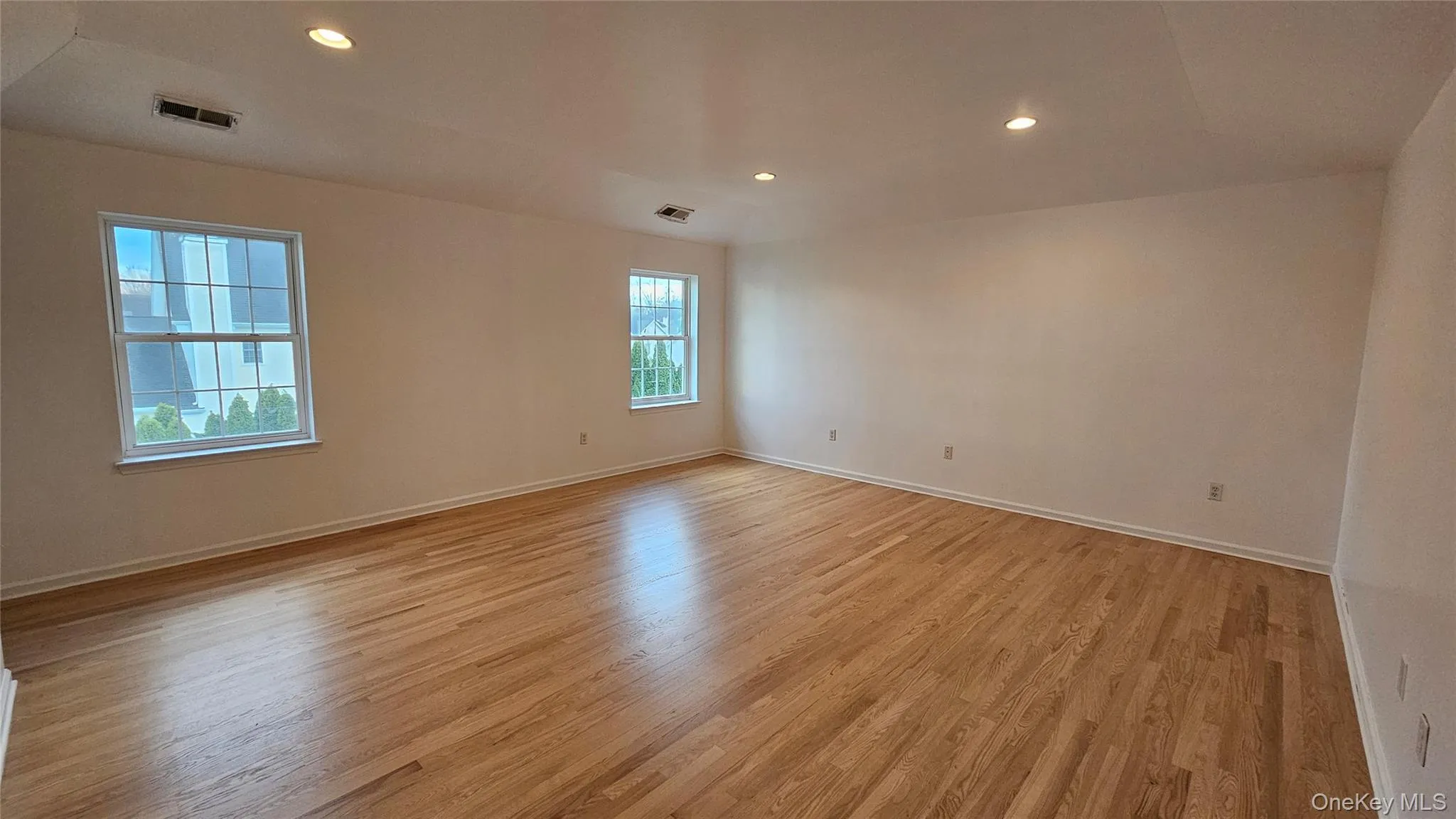 Primary bedroom featuring light wood finished floors, baseboards, and visible vents Primary bedroom featuring light wood finished floors, baseboards, and visible vents