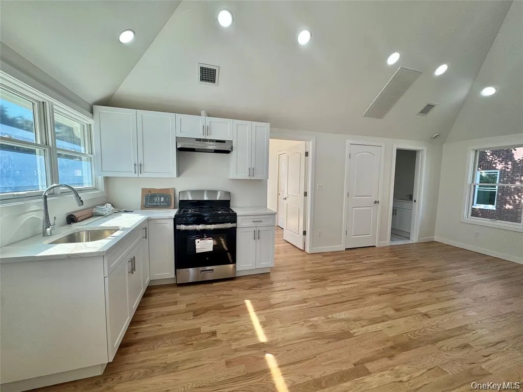 Kitchen featuring white cabinetry, stainless steel range with overhead ventilation, undermount sink, and light-toned countertops Kitchen featuring white cabinetry, stainless steel range with overhead ventilation, undermount sink, and light-toned countertops
