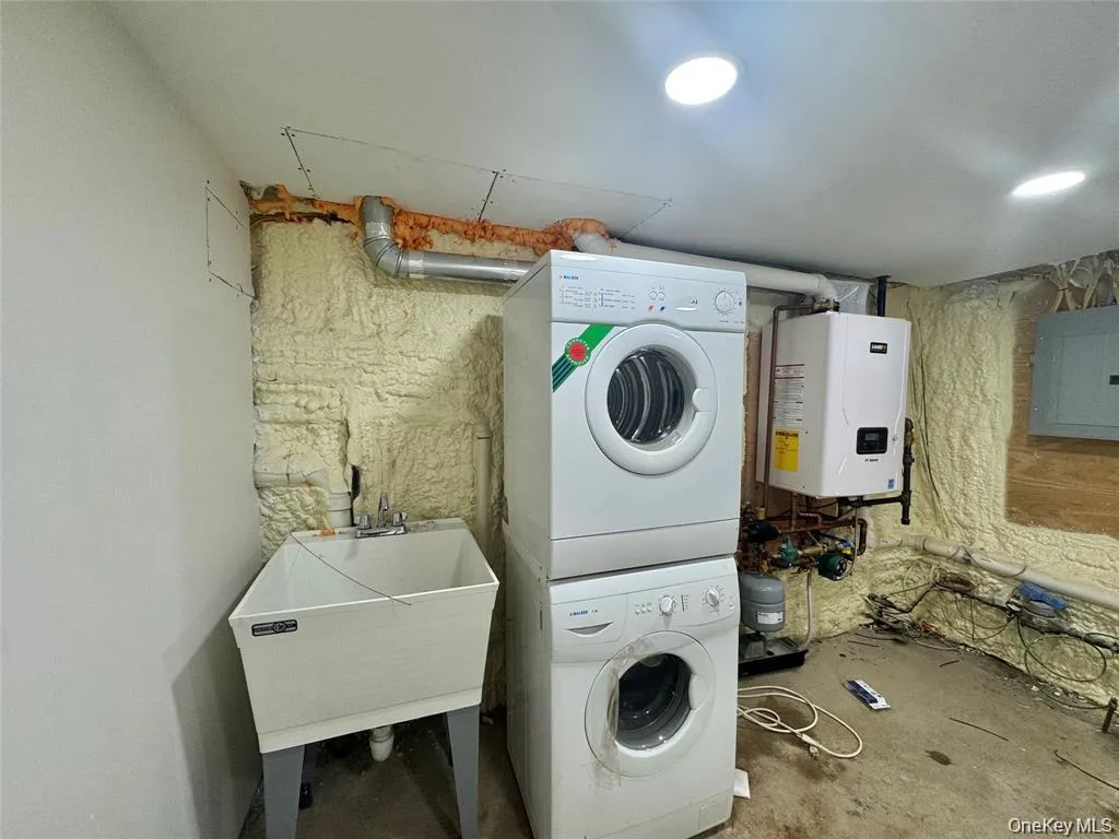 Laundry area with utility sink, stacked washer and dryer, and recessed ceiling lighting Laundry area with utility sink, stacked washer and dryer, and recessed ceiling lighting
