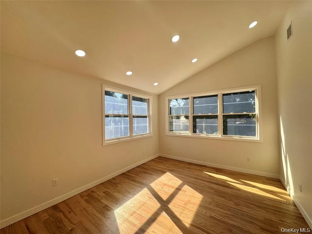 Bright corner room featuring multiple windows with natural light, recessed ceiling lighting, and warm wood-finish flooring throughout Bright corner room featuring multiple windows with natural light, recessed ceiling lighting, and warm wood-finish flooring throughout