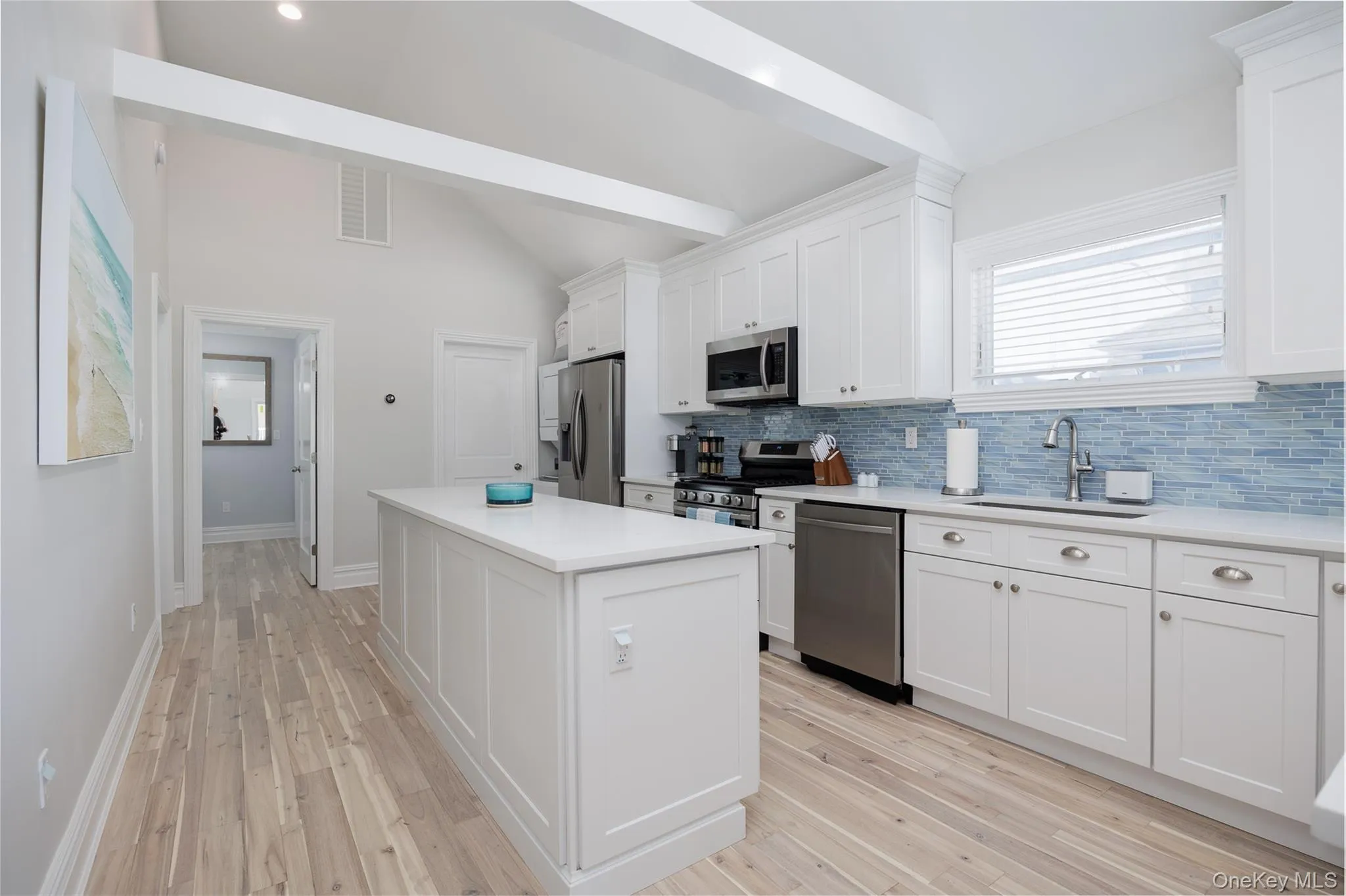 Kitchen with vaulted ceiling, appliances with stainless steel finishes, white cabinets, and a center island Kitchen with vaulted ceiling, appliances with stainless steel finishes, white cabinets, and a center island