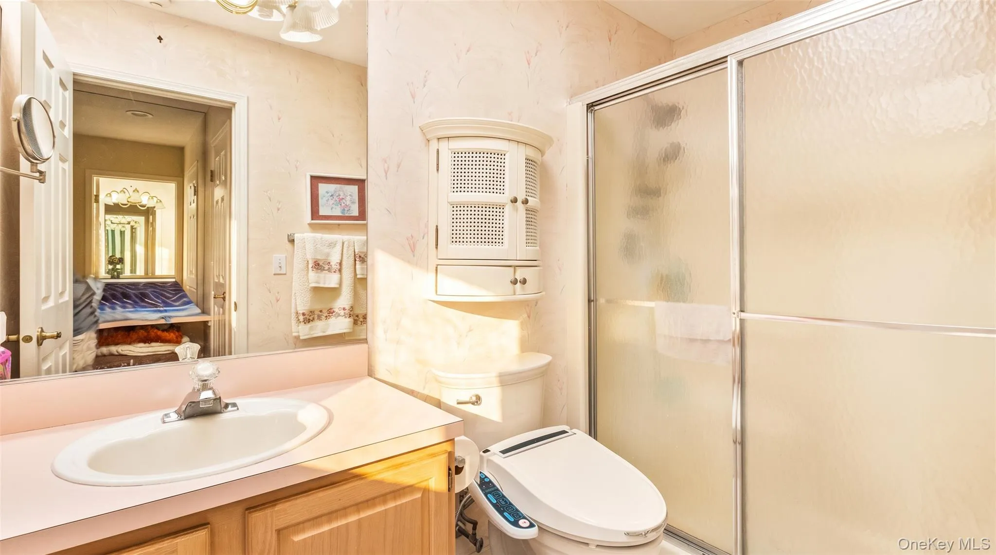 Recessed vanity mirror, laminate vanity with integrated sink, shower with sliding glass enclosure, white wall-mounted cabinet, and sconce lighting Recessed vanity mirror, laminate vanity with integrated sink, shower with sliding glass enclosure, white wall-mounted cabinet, and sconce lighting