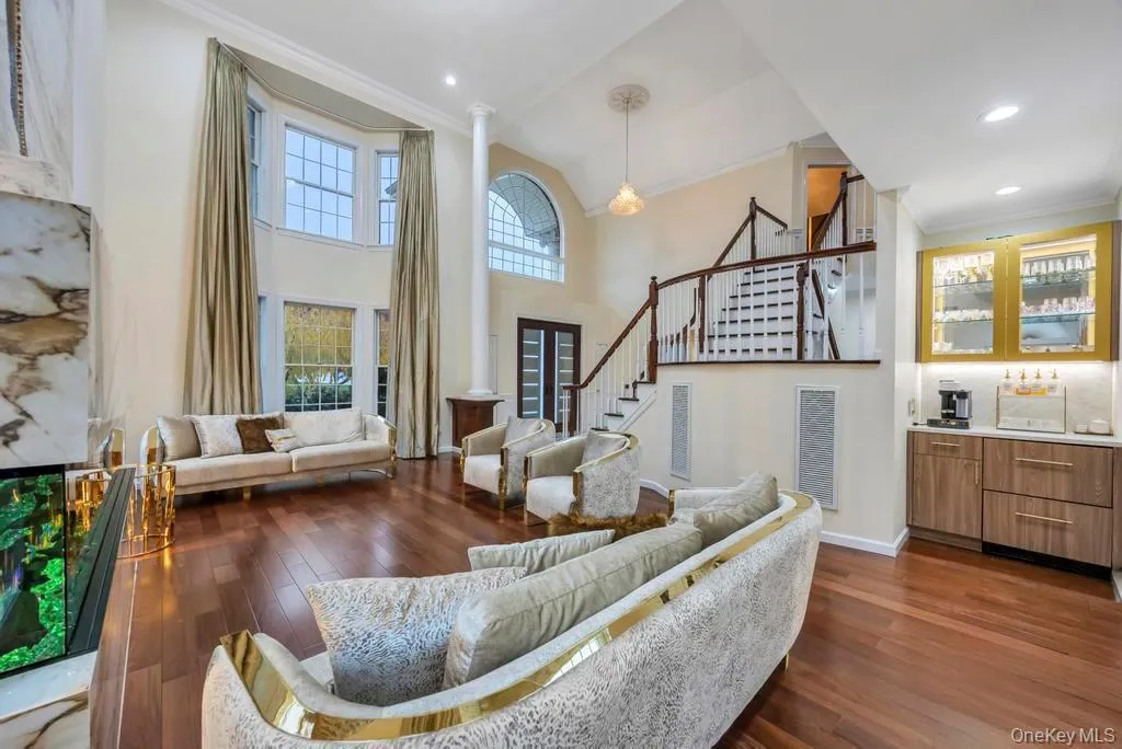 Living area with ornamental molding, stairs, dark wood finished floors, decorative columns, and a towering ceiling Living area with ornamental molding, stairs, dark wood finished floors, decorative columns, and a towering ceiling