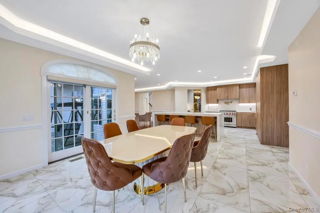 Dining space with light marble finish flooring, a chandelier, recessed lighting, a raised ceiling, and french doors Dining space with light marble finish flooring, a chandelier, recessed lighting, a raised ceiling, and french doors