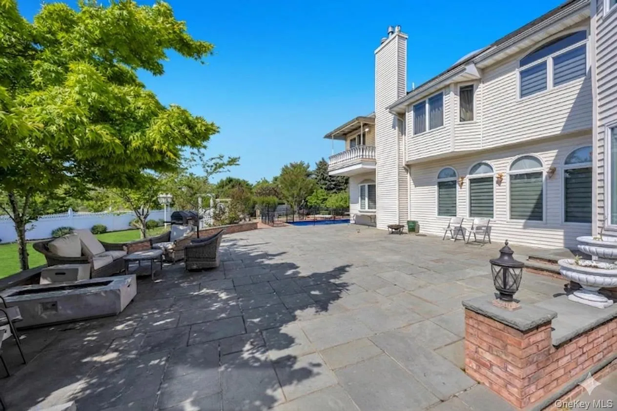 Expansive stone patio featuring a tiered fountain, brick accents, and mature trees providing natural shade Expansive stone patio featuring a tiered fountain, brick accents, and mature trees providing natural shade