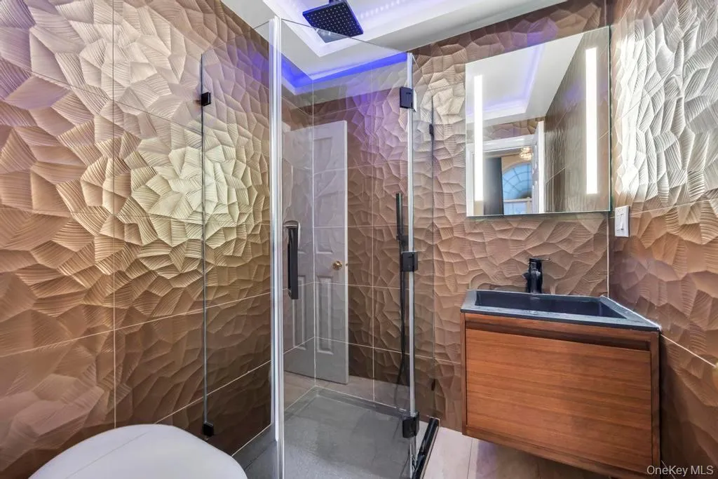 Full bath featuring tile walls, vanity, and a stall shower Full bath featuring tile walls, vanity, and a stall shower