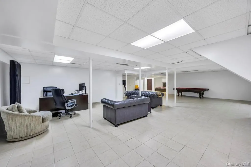 Living room featuring a desk, billiards table, a drop ceiling, and light tile patterned floors Living room featuring a desk, billiards table, a drop ceiling, and light tile patterned floors