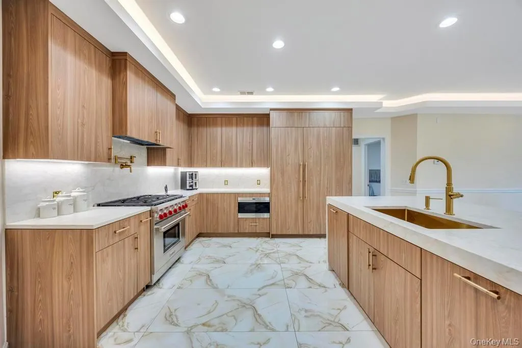 Kitchen with light marble finish floors, light stone counters, luxury range, recessed lighting, and tasteful backsplash Kitchen with light marble finish floors, light stone counters, luxury range, recessed lighting, and tasteful backsplash
