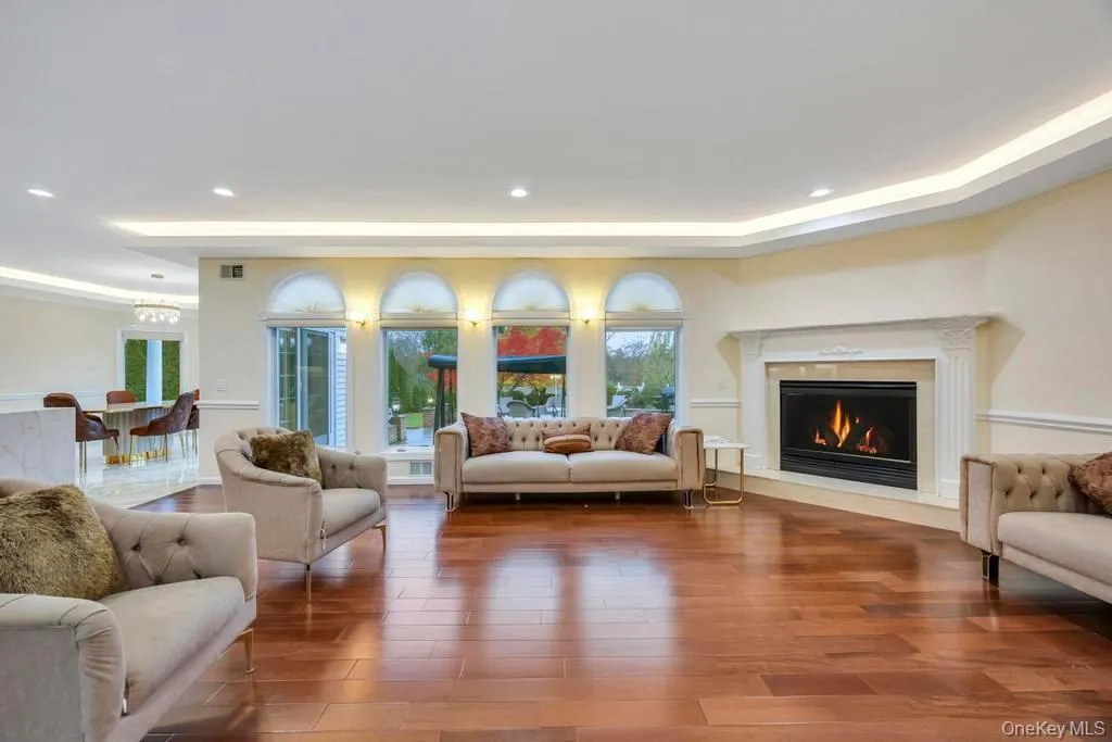 Living area with recessed lighting, wood finished floors, a tray ceiling, and a premium fireplace Living area with recessed lighting, wood finished floors, a tray ceiling, and a premium fireplace