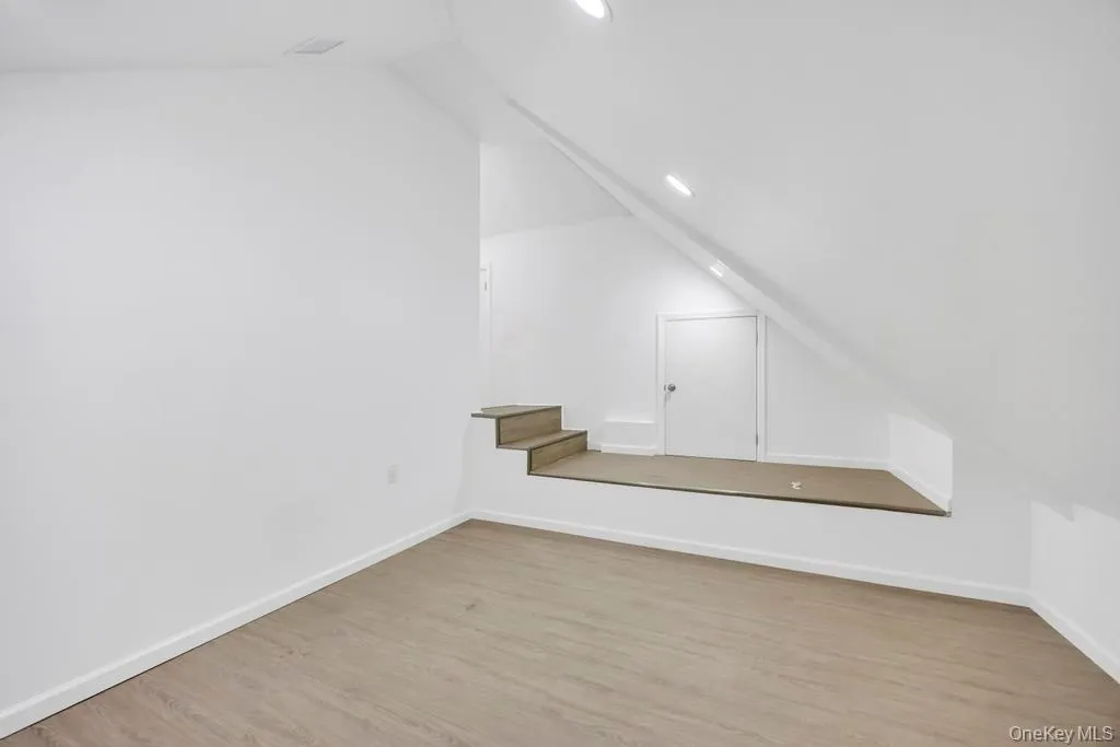 Additional living space with vaulted ceiling, light wood-style flooring, and recessed lighting Additional living space with vaulted ceiling, light wood-style flooring, and recessed lighting