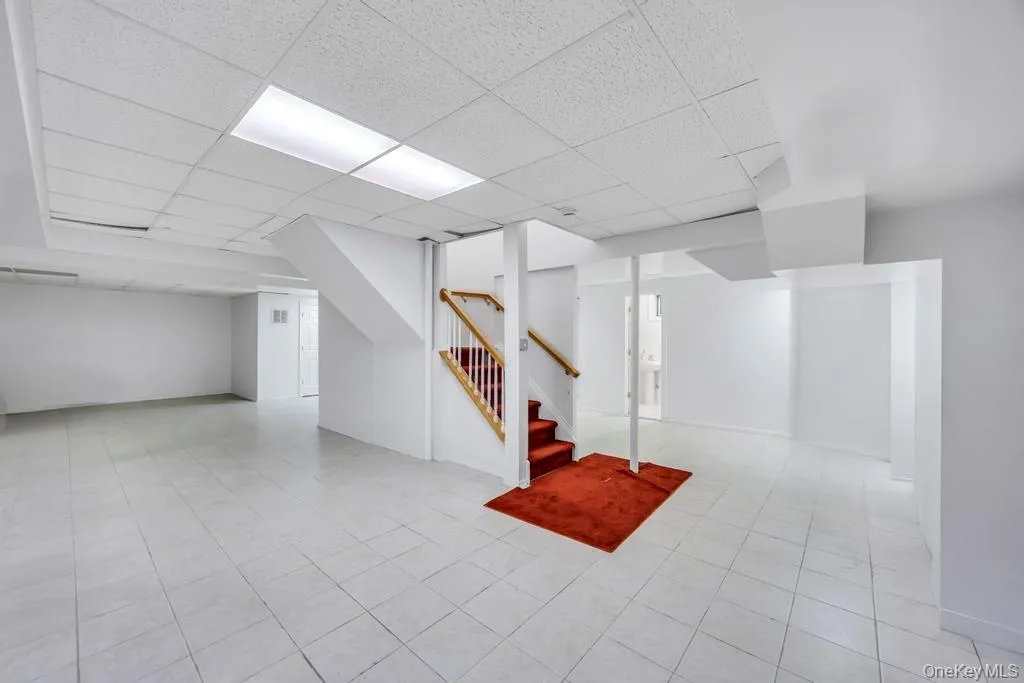 Finished basement with stairs, a paneled ceiling, and light tile patterned floors Finished basement with stairs, a paneled ceiling, and light tile patterned floors