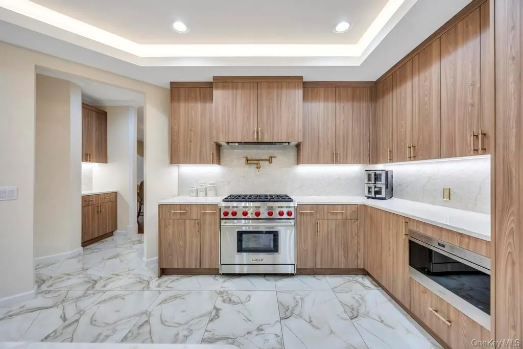 Kitchen featuring light marble finish flooring, appliances with stainless steel finishes, tasteful backsplash, modern cabinets, and recessed lighting Kitchen featuring light marble finish flooring, appliances with stainless steel finishes, tasteful backsplash, modern cabinets, and recessed lighting