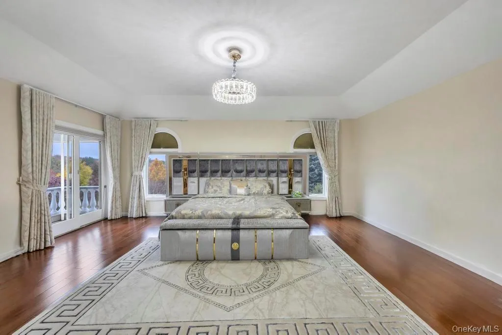 Bedroom featuring access to exterior, dark wood-style floors, and a chandelier Bedroom featuring access to exterior, dark wood-style floors, and a chandelier