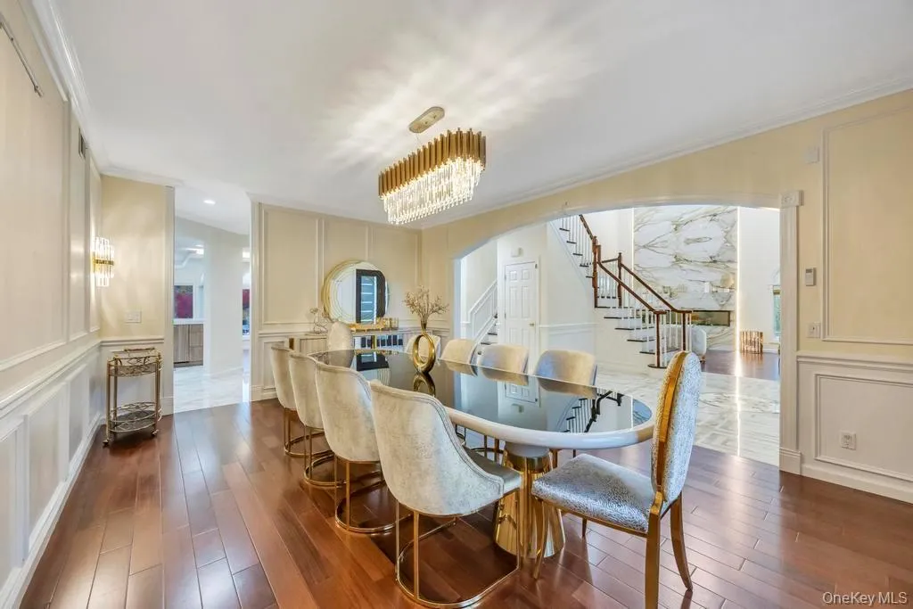 Dining space featuring a decorative wall, stairs, a chandelier, dark wood-type flooring, and arched walkways Dining space featuring a decorative wall, stairs, a chandelier, dark wood-type flooring, and arched walkways