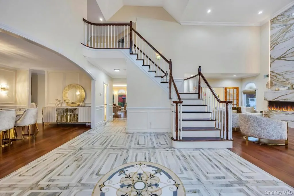 Foyer featuring dark wood finished floors, a large fireplace, a decorative wall, stairs, and a high ceiling Foyer featuring dark wood finished floors, a large fireplace, a decorative wall, stairs, and a high ceiling