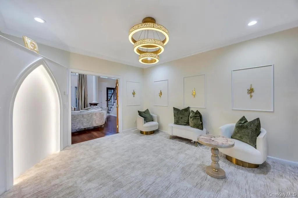 Living area with carpet flooring, recessed lighting, a chandelier, ornamental molding, and stairs Living area with carpet flooring, recessed lighting, a chandelier, ornamental molding, and stairs
