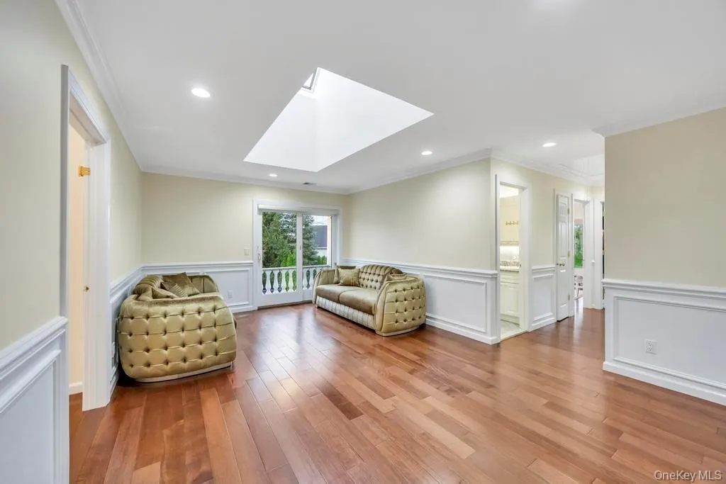 Sitting room with wainscoting, crown molding, a decorative wall, a skylight, and wood finished floors Sitting room with wainscoting, crown molding, a decorative wall, a skylight, and wood finished floors