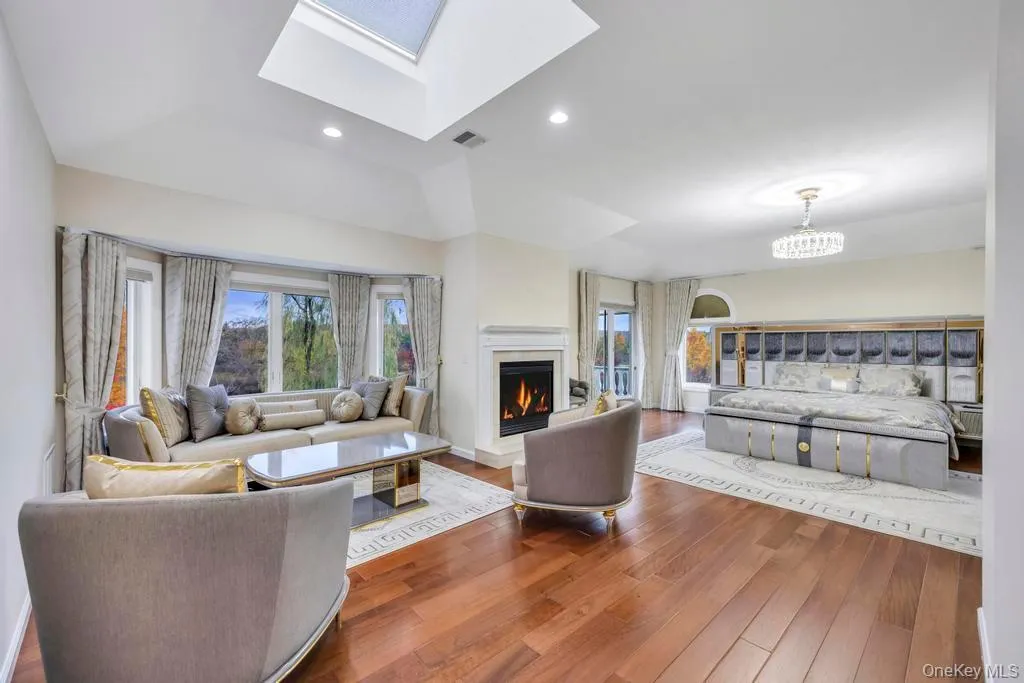 Living area with wood finished floors, a lit fireplace, a skylight, and recessed lighting Living area with wood finished floors, a lit fireplace, a skylight, and recessed lighting