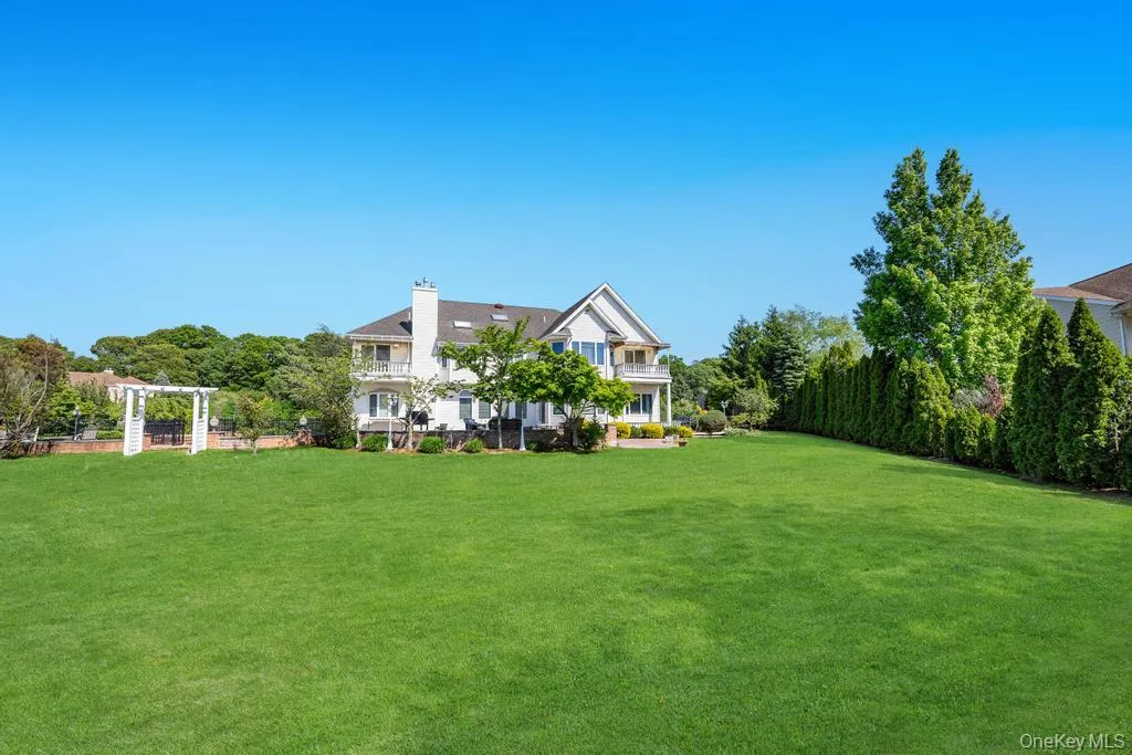 Expansive green lawn with a white multi-story residence Expansive green lawn with a white multi-story residence