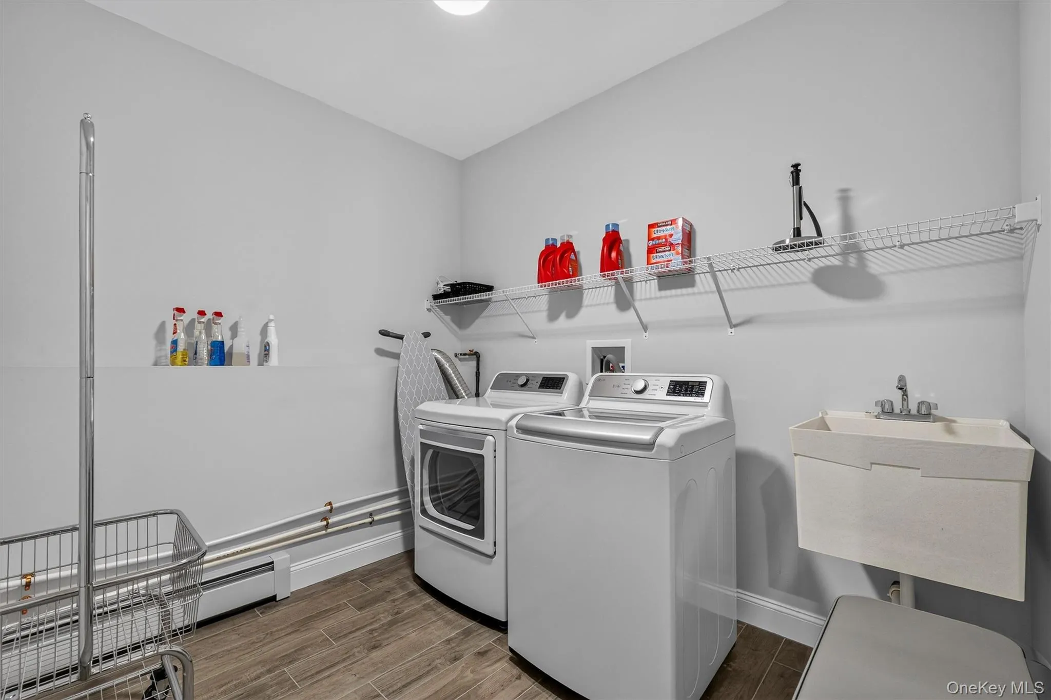 Utility room with wood-finish flooring, built-in wire shelving, and a utility sink Utility room with wood-finish flooring, built-in wire shelving, and a utility sink