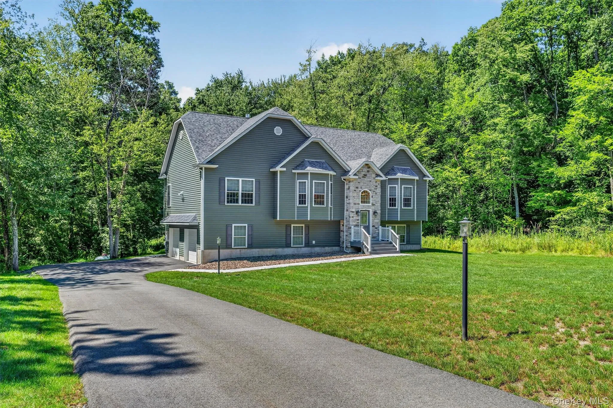 Contemporary residence featuring a stone facade, multi-pane windows with shutters, and a paved driveway Contemporary residence featuring a stone facade, multi-pane windows with shutters, and a paved driveway