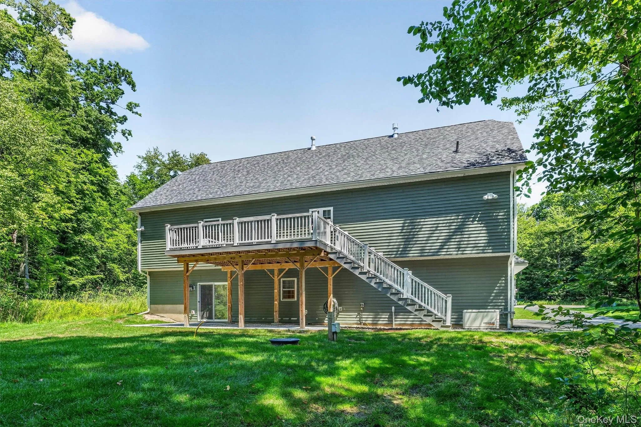 Exterior featuring a raised deck with white railings, a grey shingle roof, green siding, and a ground-level sliding glass door Exterior featuring a raised deck with white railings, a grey shingle roof, green siding, and a ground-level sliding glass door