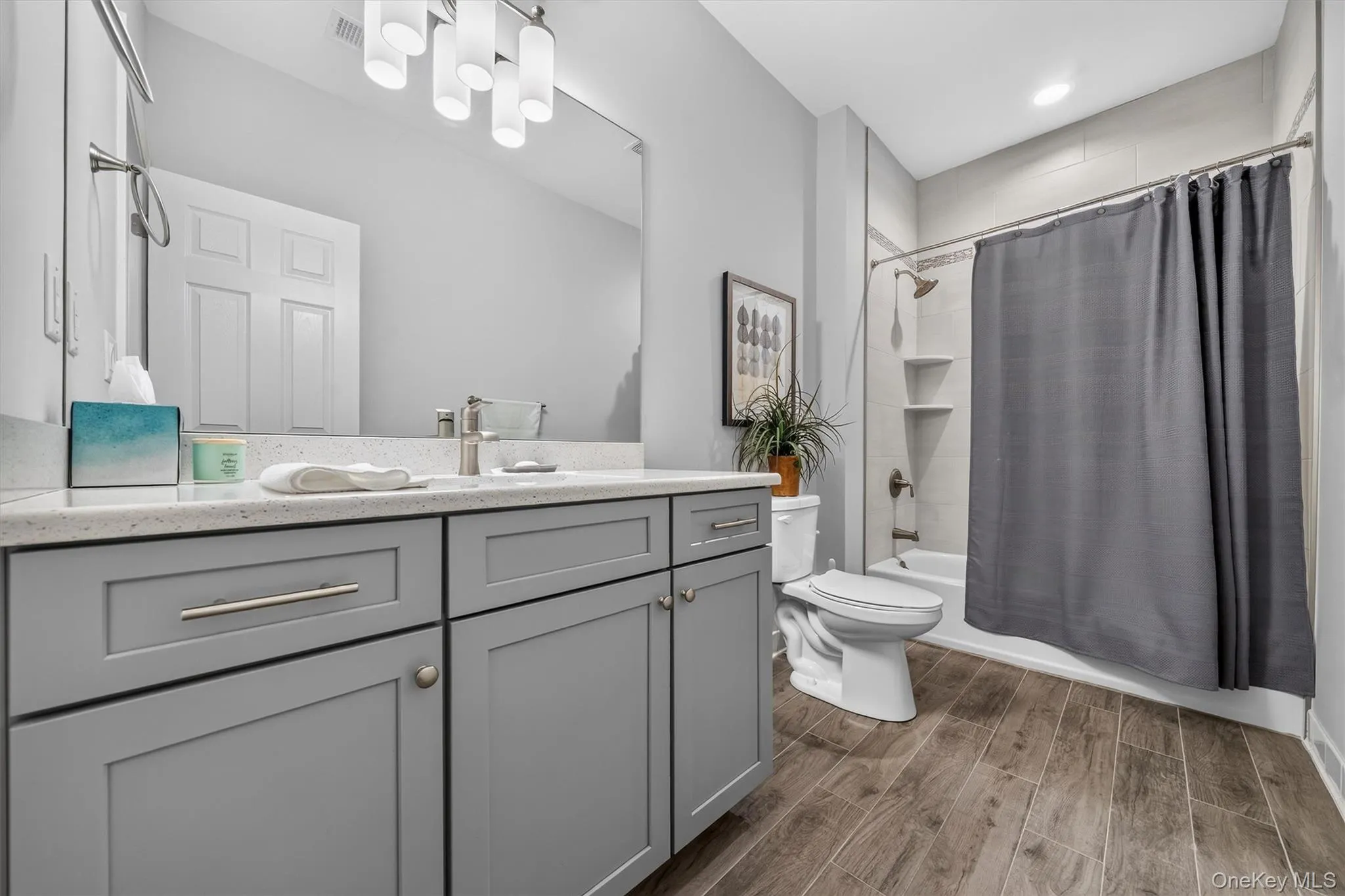 Spa-inspired bathroom featuring a gray cabinetry vanity with dual-sink configuration, white quartz countertop, and chrome hardware Spa-inspired bathroom featuring a gray cabinetry vanity with dual-sink configuration, white quartz countertop, and chrome hardware