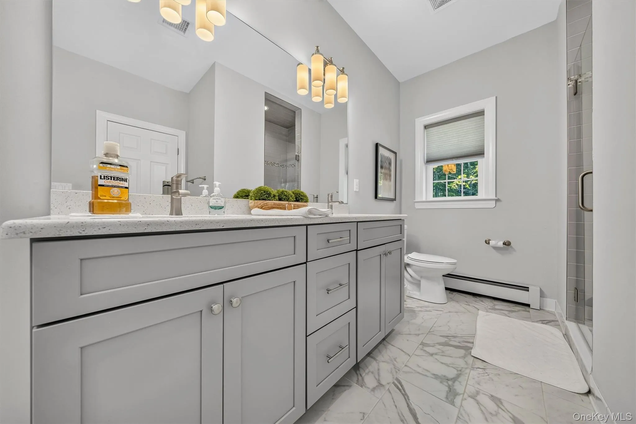Dual vanity with shaker-style cabinetry, a stone countertop, and a large wall mirror Dual vanity with shaker-style cabinetry, a stone countertop, and a large wall mirror