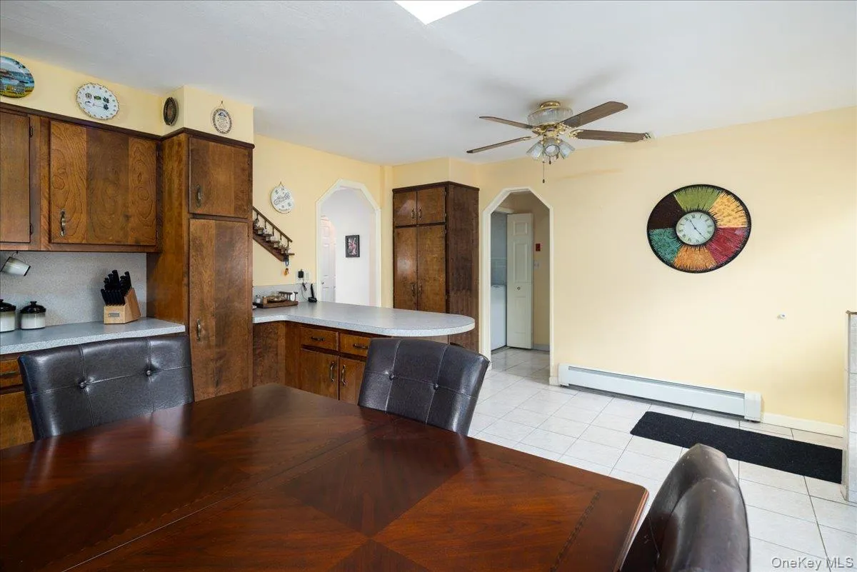 Kitchen featuring wood cabinetry, white countertops, and white tile flooring Kitchen featuring wood cabinetry, white countertops, and white tile flooring