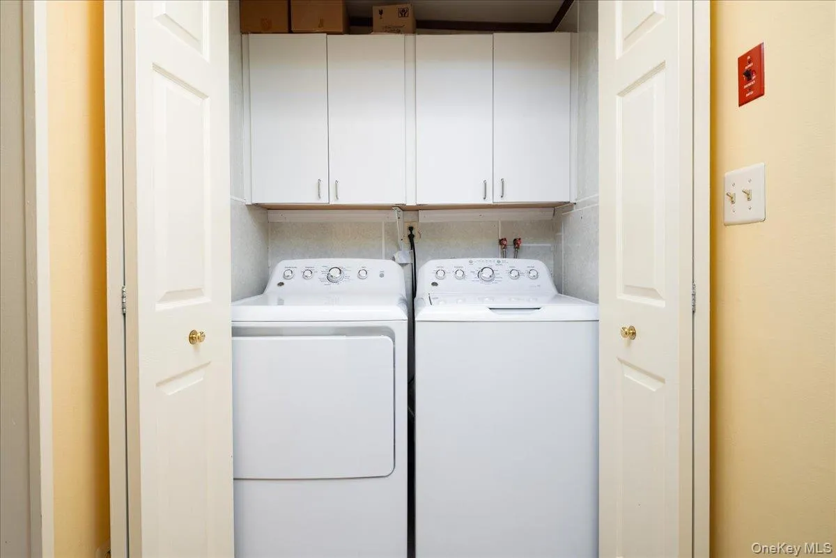 Laundry closet featuring upper cabinetry and a full-size washer and dryer Laundry closet featuring upper cabinetry and a full-size washer and dryer
