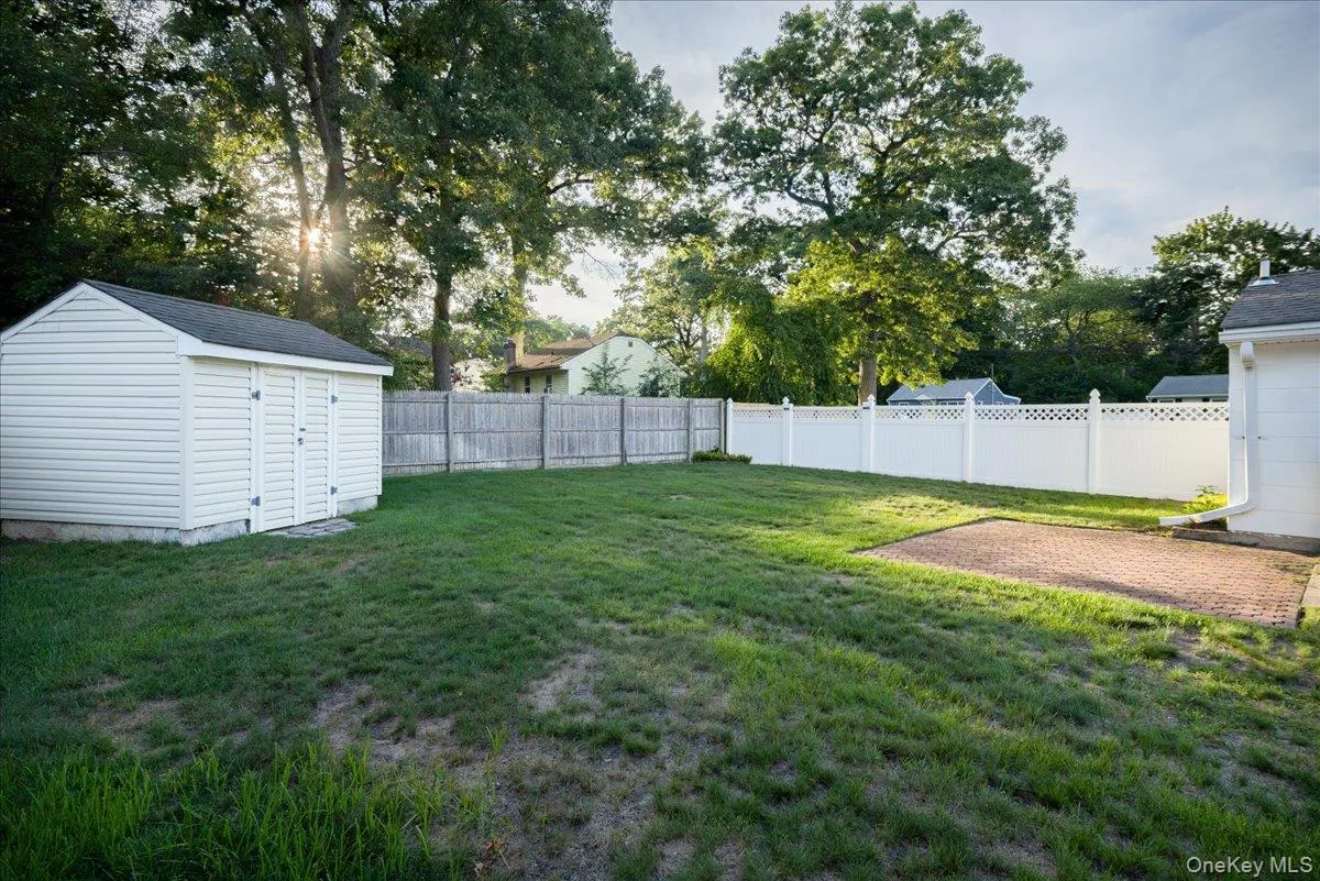 Expansive green space featuring a white vinyl shed, a section of wood privacy fencing, and a white lattice-top fence Expansive green space featuring a white vinyl shed, a section of wood privacy fencing, and a white lattice-top fence