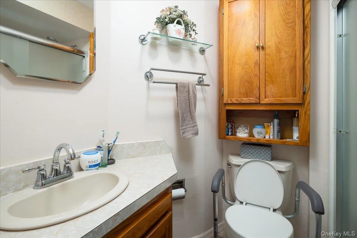 Vanity with integrated sink, wall-mounted mirror, and wood-finish cabinetry Vanity with integrated sink, wall-mounted mirror, and wood-finish cabinetry
