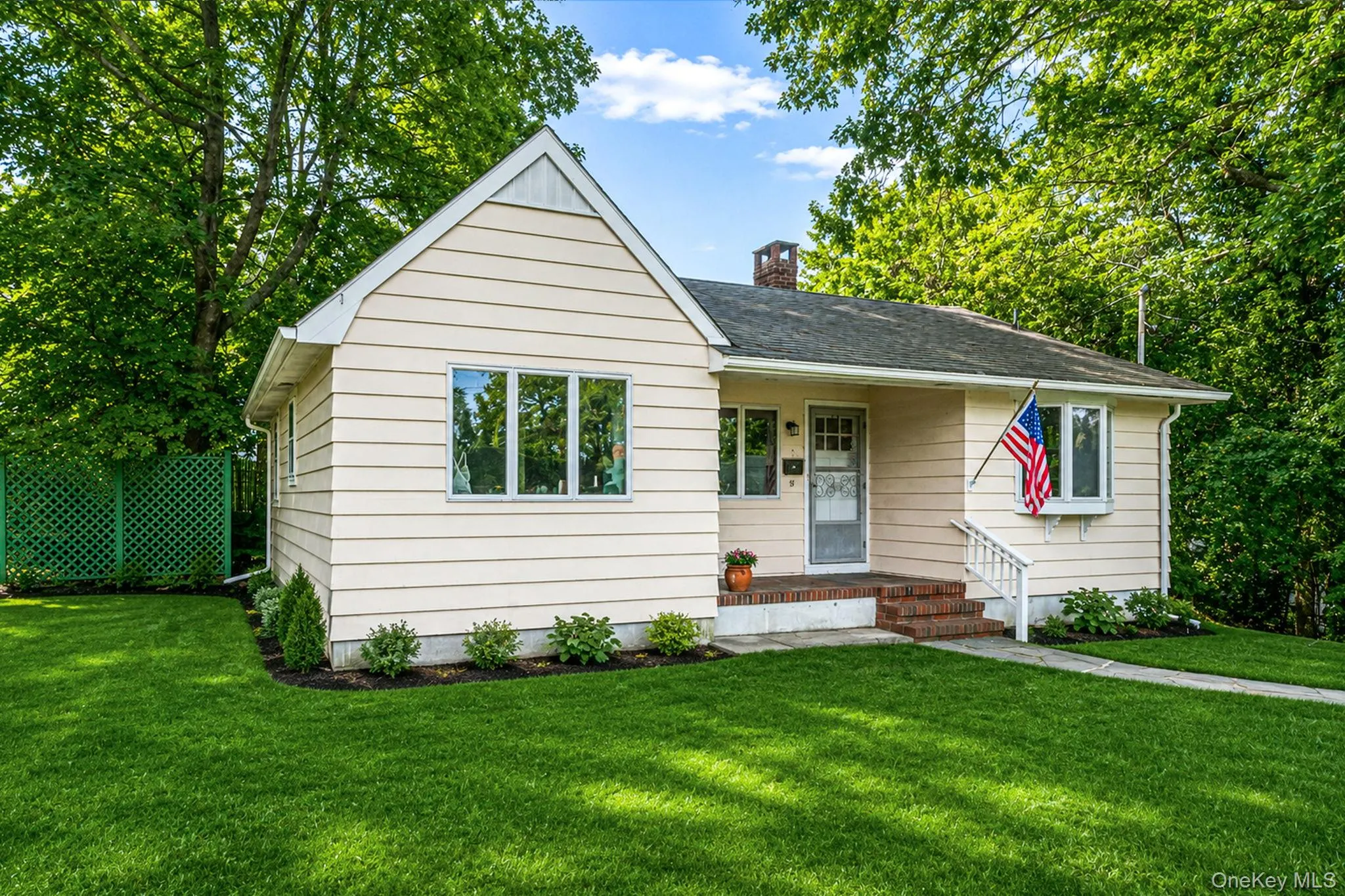 Manicured lawn, mature trees, light-colored siding, brick entryway, white-framed windows Manicured lawn, mature trees, light-colored siding, brick entryway, white-framed windows