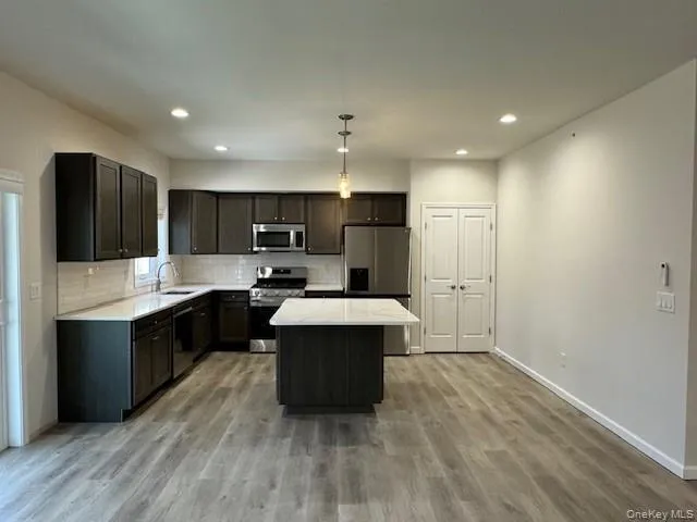 Kitchen featuring sink, decorative light fixtures, a center island, stainless steel appliances, and backsplash Kitchen featuring sink, decorative light fixtures, a center island, stainless steel appliances, and backsplash
