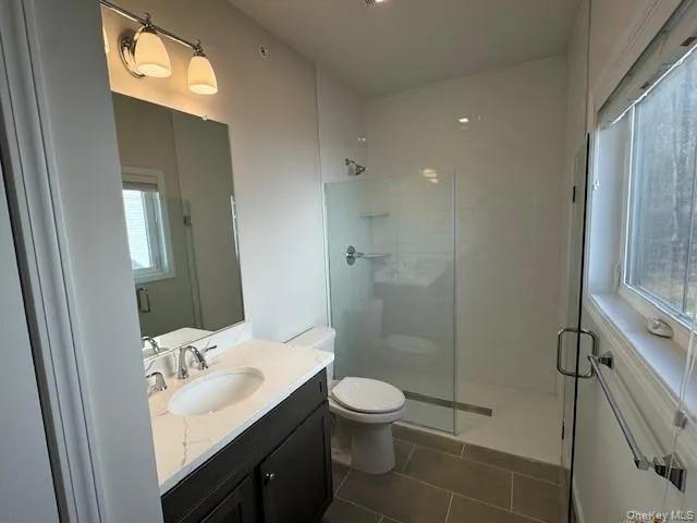 Bathroom featuring walk in shower, tile patterned floors, toilet, and vanity Bathroom featuring walk in shower, tile patterned floors, toilet, and vanity