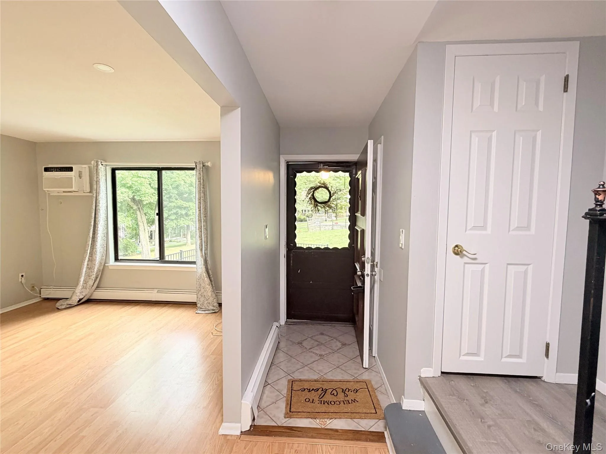 Wood-finish flooring throughout the living space, a window with exterior views, and a paneled interior door Wood-finish flooring throughout the living space, a window with exterior views, and a paneled interior door