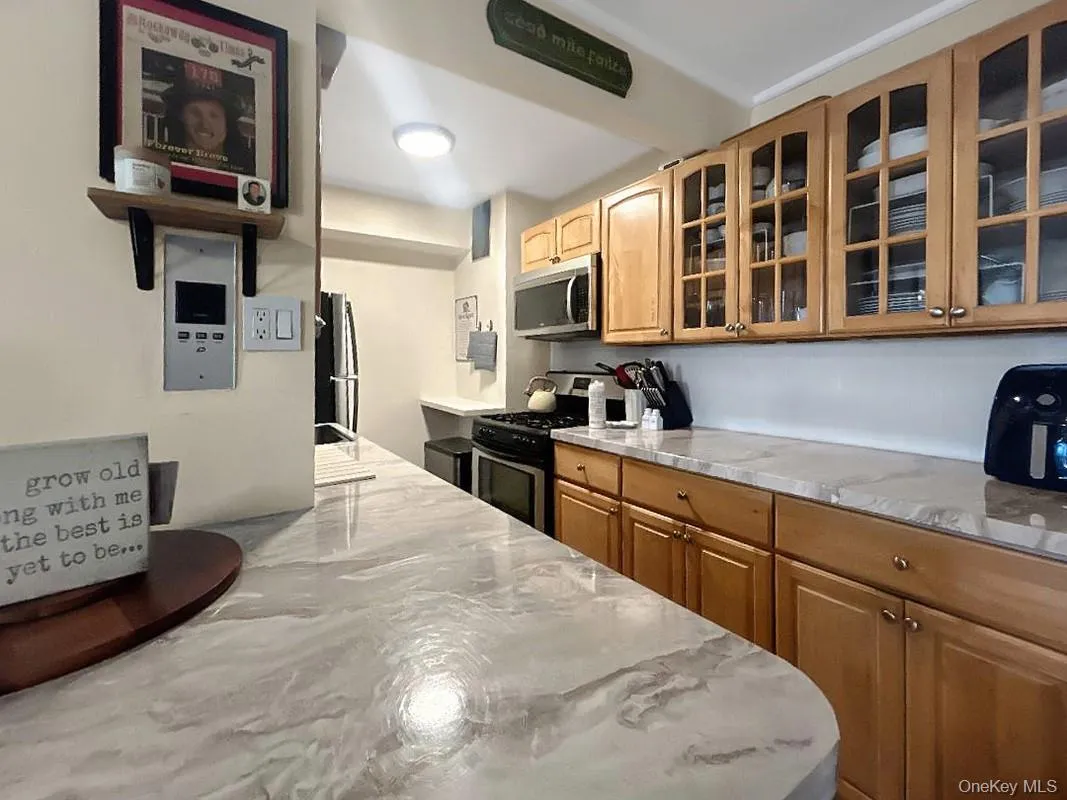Kitchen featuring wood cabinetry, glass-front upper cabinets, and a stainless steel microwave Kitchen featuring wood cabinetry, glass-front upper cabinets, and a stainless steel microwave