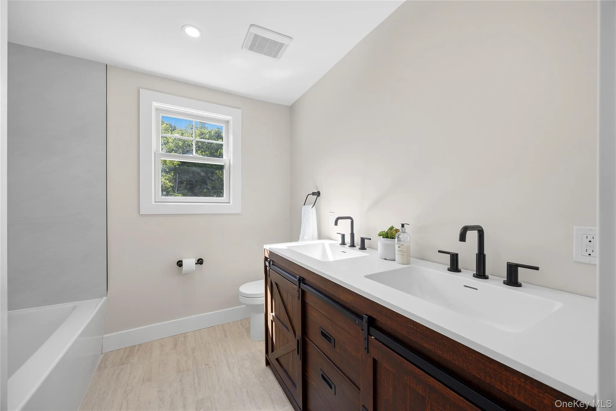 Dual sink vanity with matte black fixtures and dark wood-finish cabinetry Dual sink vanity with matte black fixtures and dark wood-finish cabinetry