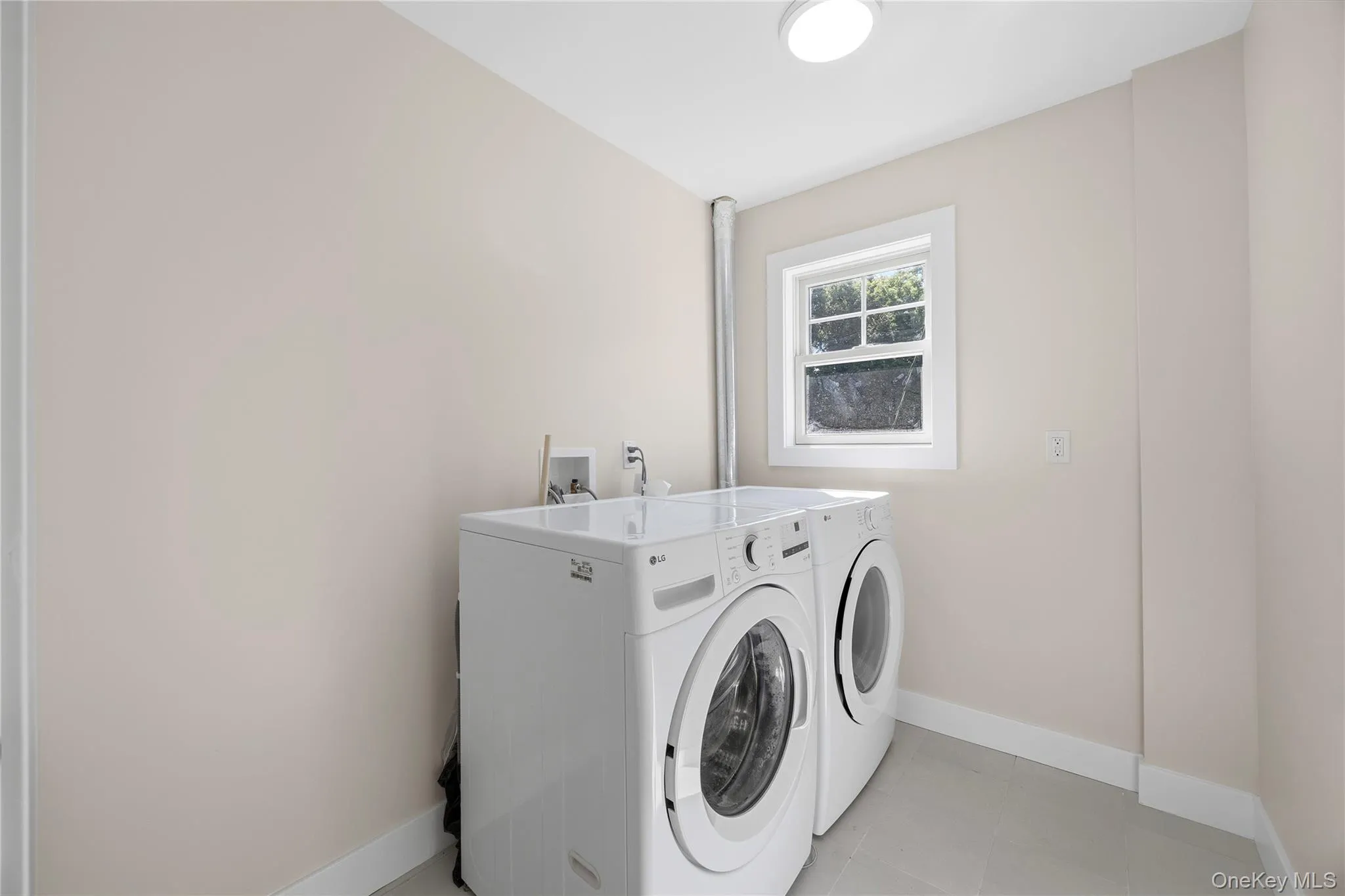 Dedicated laundry space with window, ceiling-mounted light fixture, and light-colored walls Dedicated laundry space with window, ceiling-mounted light fixture, and light-colored walls
